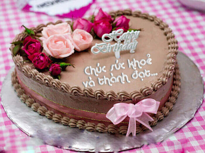 Bánh kem sinh nhật màu hồng với những bông hoa xung quanh
